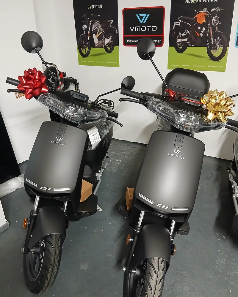 Zwei schwarze Vmoto CU Elektroroller mit Übergabeschleifen am Lenker, abholbereit im Showroom in Mannheim.