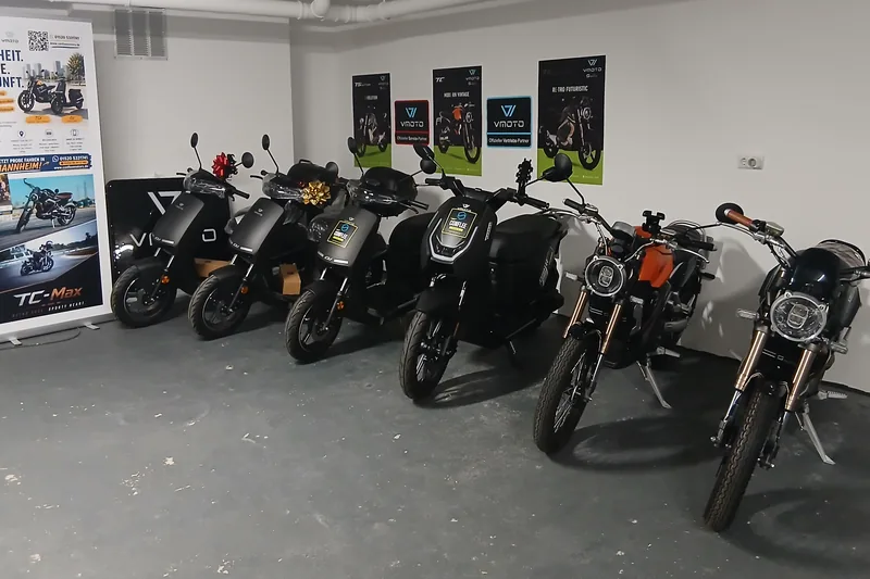 Weiter Blick durch den Showroom in Mannheim: Elektroroller und E-Motorräder nebeneinander vor der hellen Wand.
