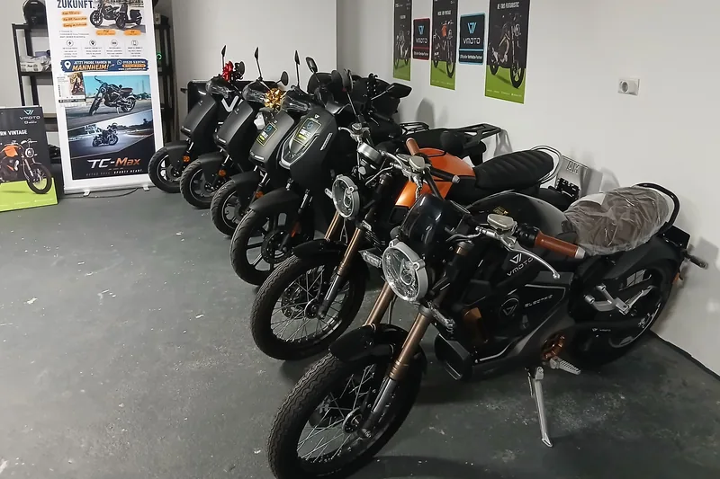 Tiefe Perspektive auf zwei E-Motorräder im Showroom in Mannheim, Speichenrad und Scheinwerfer im Vordergrund.